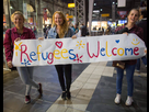 https://image.noelshack.com/fichiers/2021/34/7/1630254503-1496568036-girls-standing-with-sign-welcoming-migrants-70132.jpg